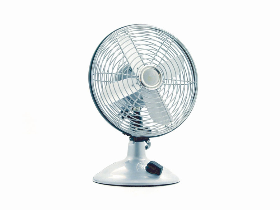 Close-up of a classic electric desk fan against a white background, showcasing retro design.